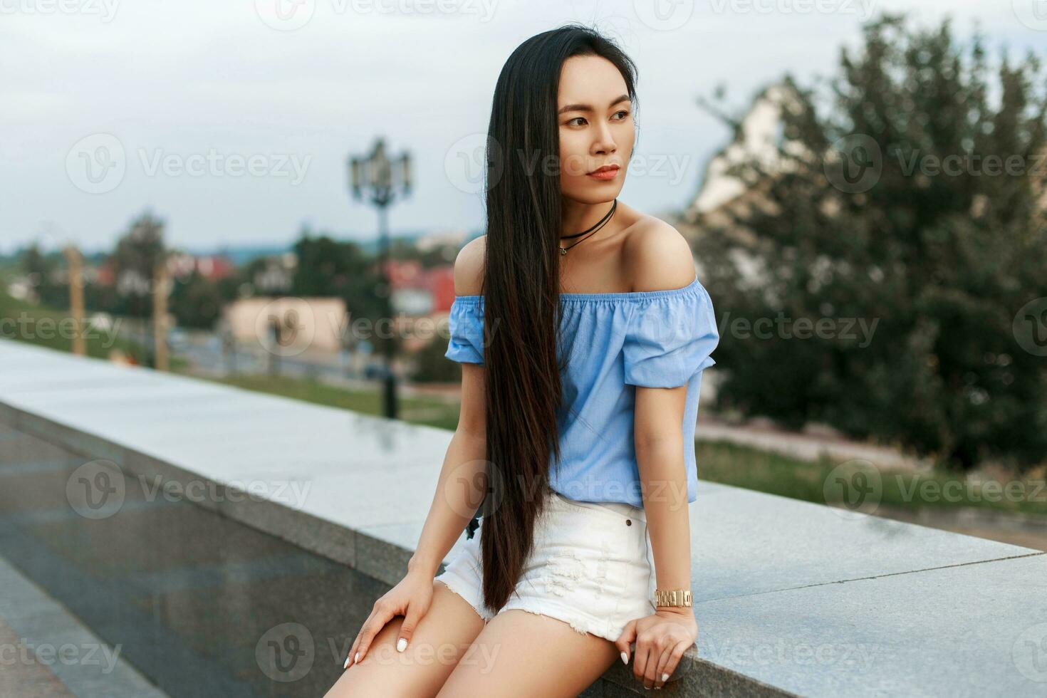 magnifique fille avec longue noir cheveux repos sur une ville Contexte. photo