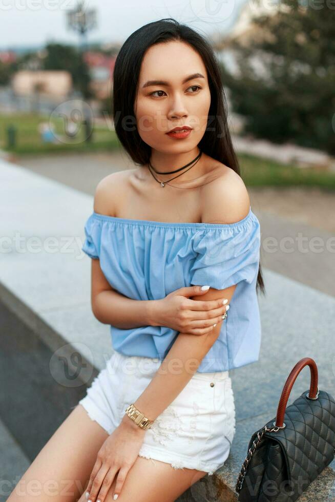 asiatique femme dans une bleu chemisier et blanc short avec une sac photo