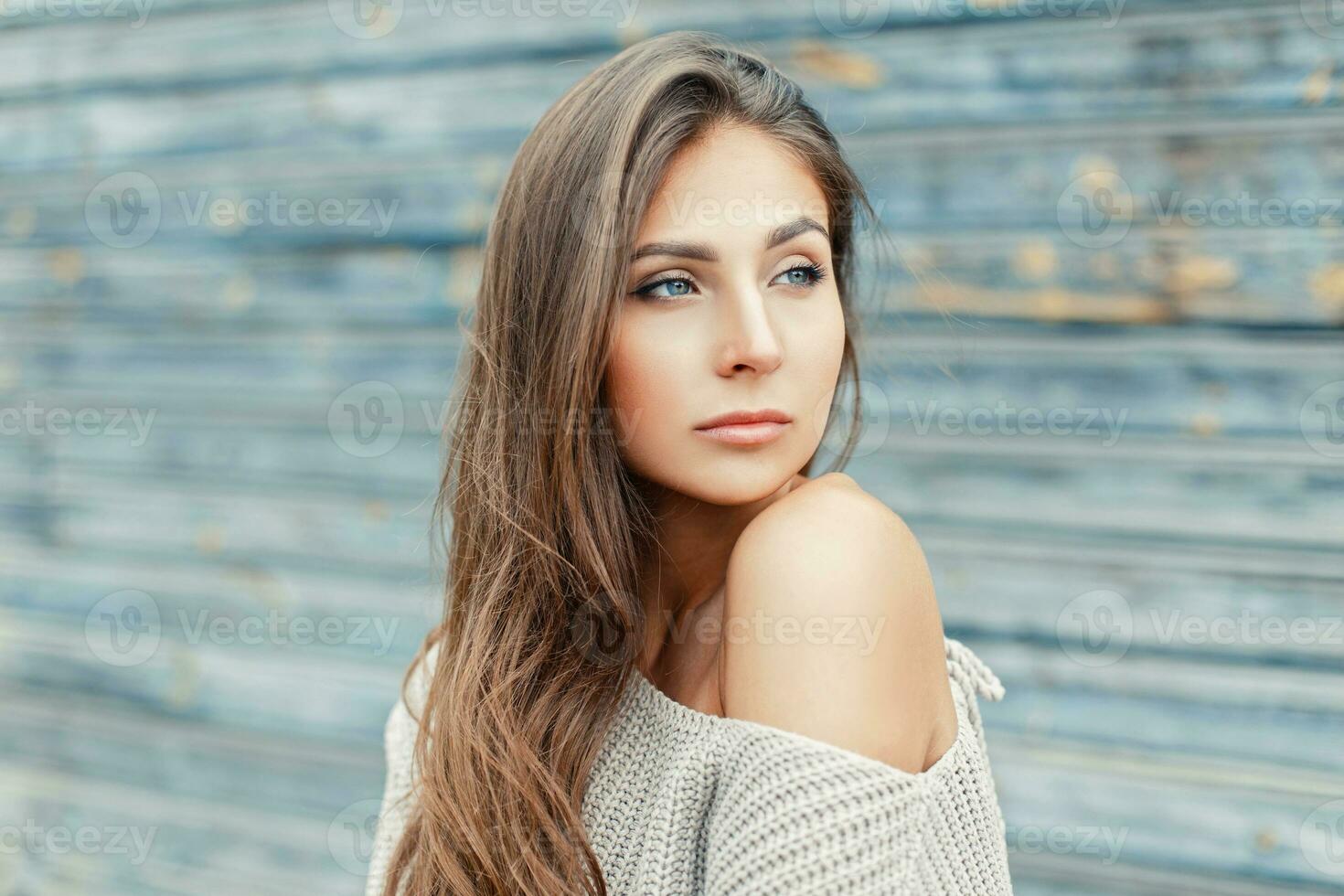 sexy Jeune femme dans une gris chandail et nu épaule près le en bois mur photo