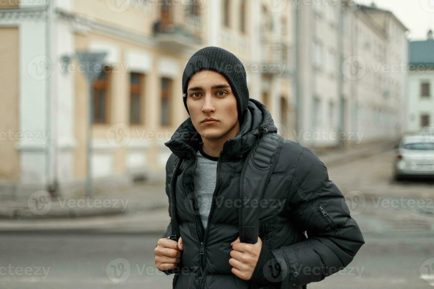 Beau Jeune homme dans hiver veste et tricoté noir chapeau sur ville  Contexte 23335648 Photo de stock chez Vecteezy