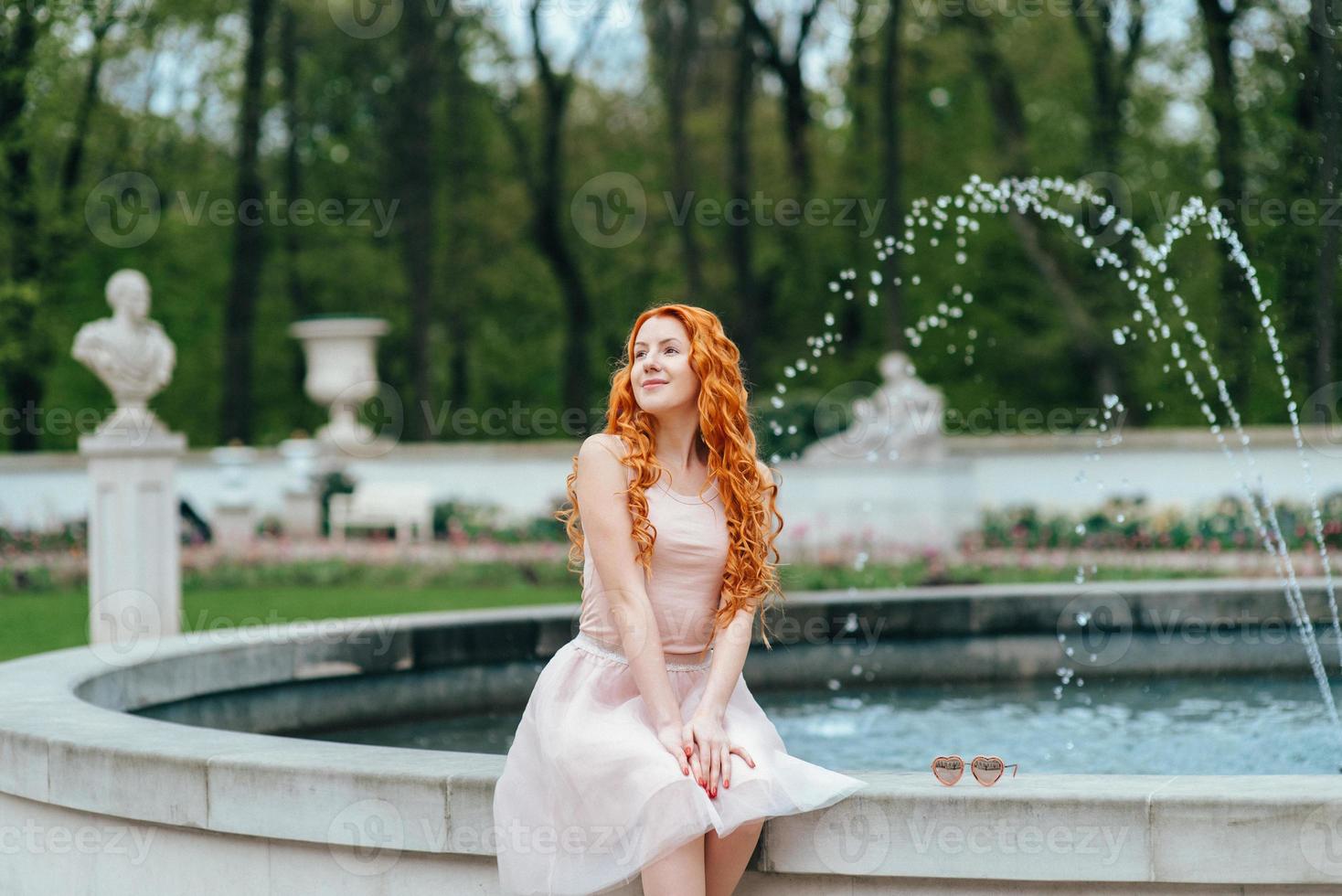 Jeune fille rousse marchant dans un parc entre les arbres photo