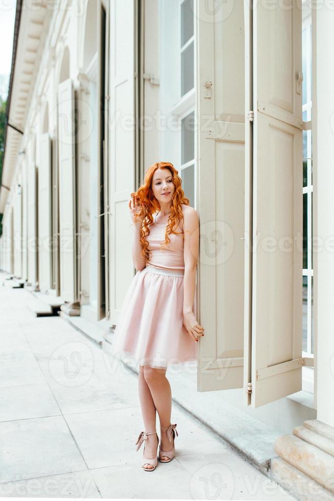 Jeune fille rousse marchant dans un parc entre les arbres et les objets architecturaux photo