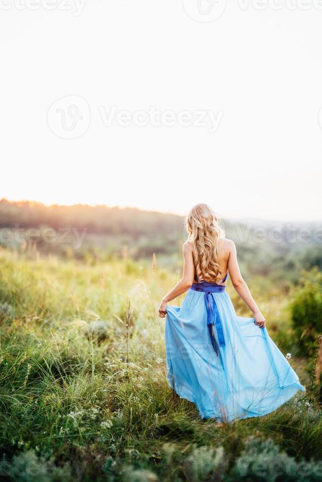 Fille blonde aux cheveux lâches dans une robe bleu clair et un mec à la lumière du coucher du soleil photo