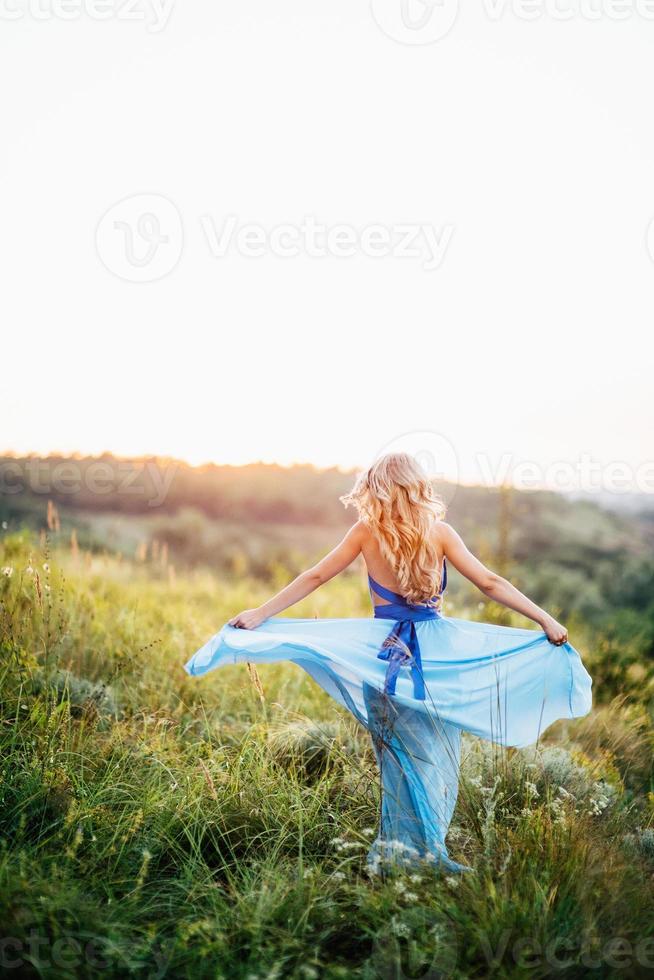 Fille blonde aux cheveux lâches dans une robe bleu clair et un mec à la lumière du coucher du soleil photo