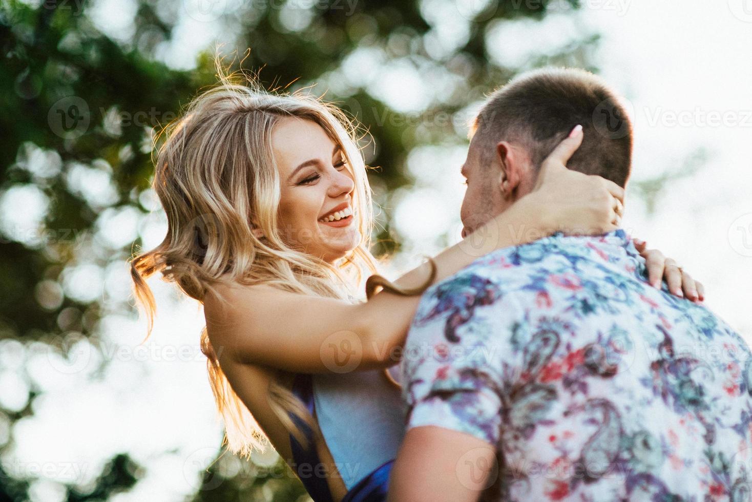 Fille blonde aux cheveux lâches dans une robe bleu clair et un mec à la lumière du coucher du soleil photo