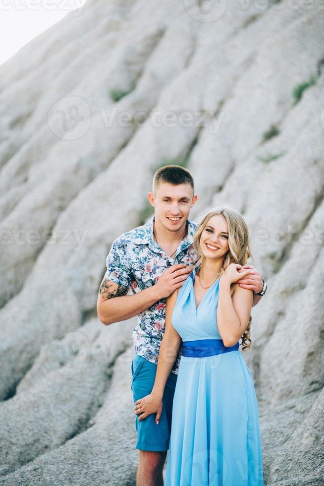 Fille blonde dans une robe bleu clair et un gars dans une chemise légère dans une carrière de granit photo