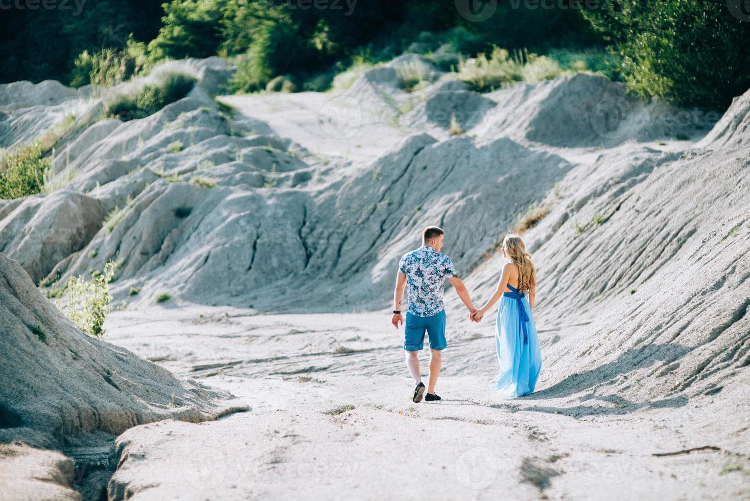 Fille blonde dans une robe bleu clair et un gars dans une chemise légère dans une carrière de granit photo