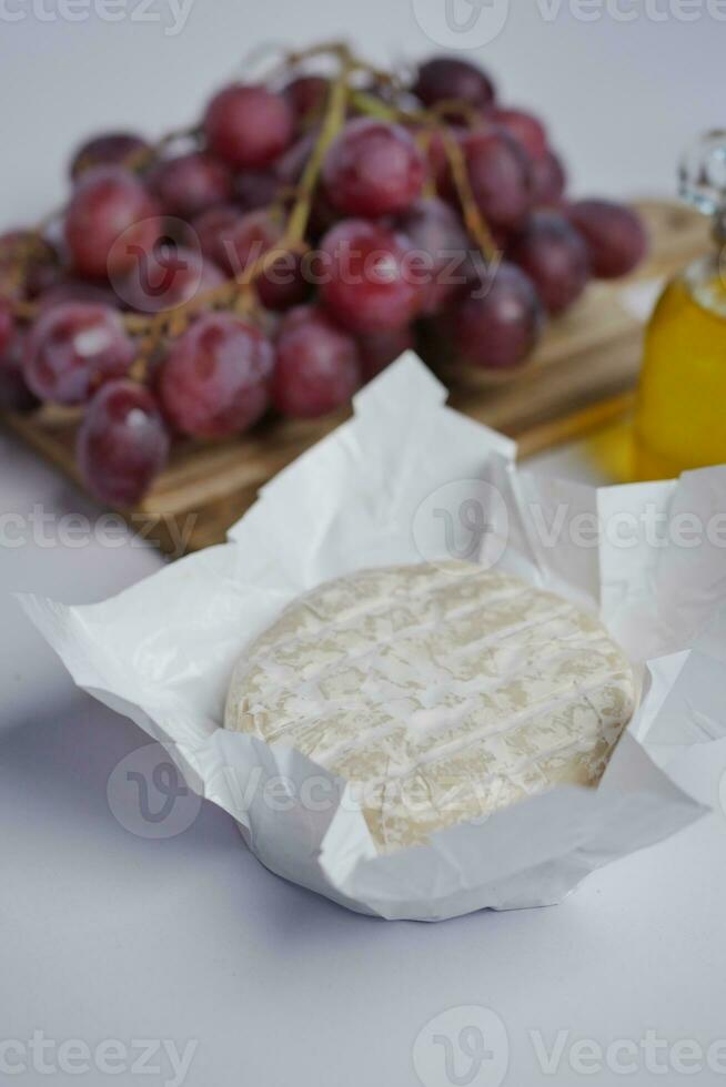 Camembert fromage , grain de raisin et pétrole sur table photo