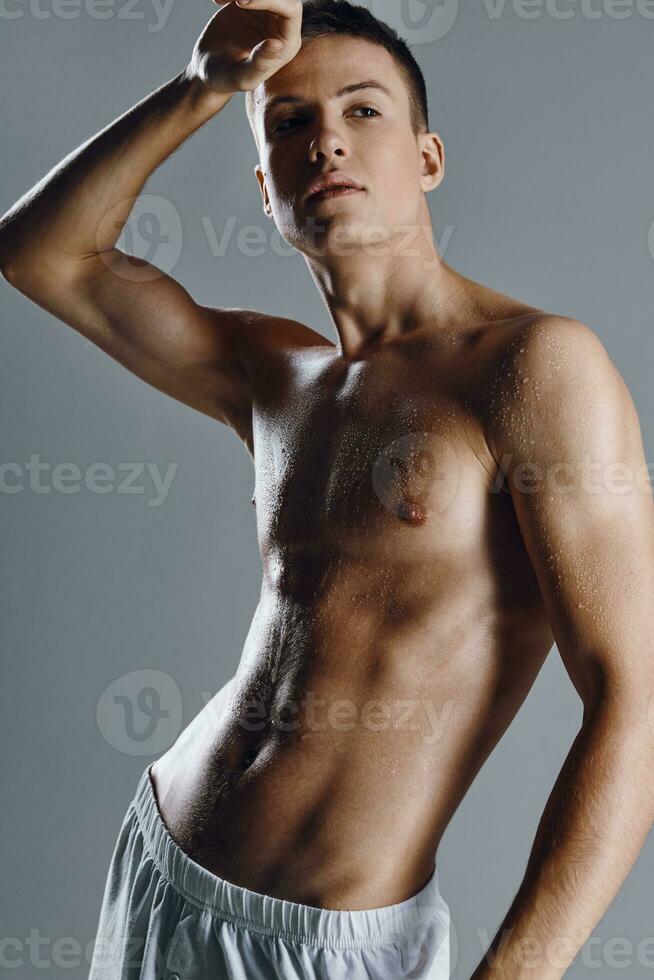 gars bodybuilder avec pompé en haut bras muscles sur gris Contexte tondu vue fermer photo