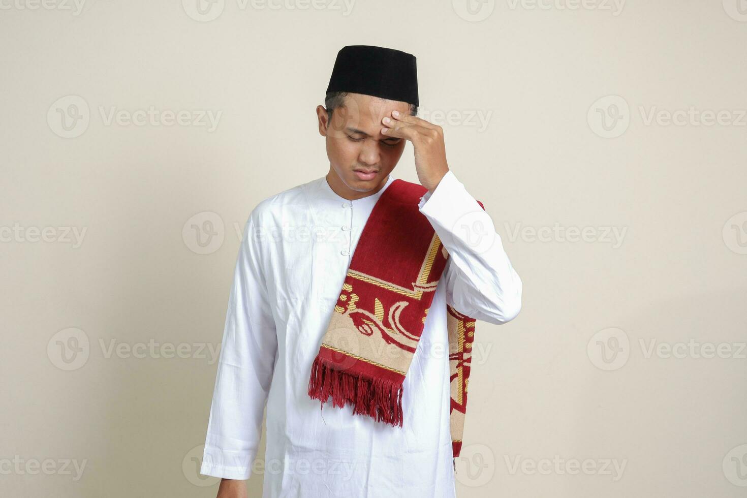 portrait de attrayant asiatique musulman homme dans blanc chemise ayant une migraine, émouvant le sien temple. mal de crâne maladie concept. isolé image sur gris Contexte photo