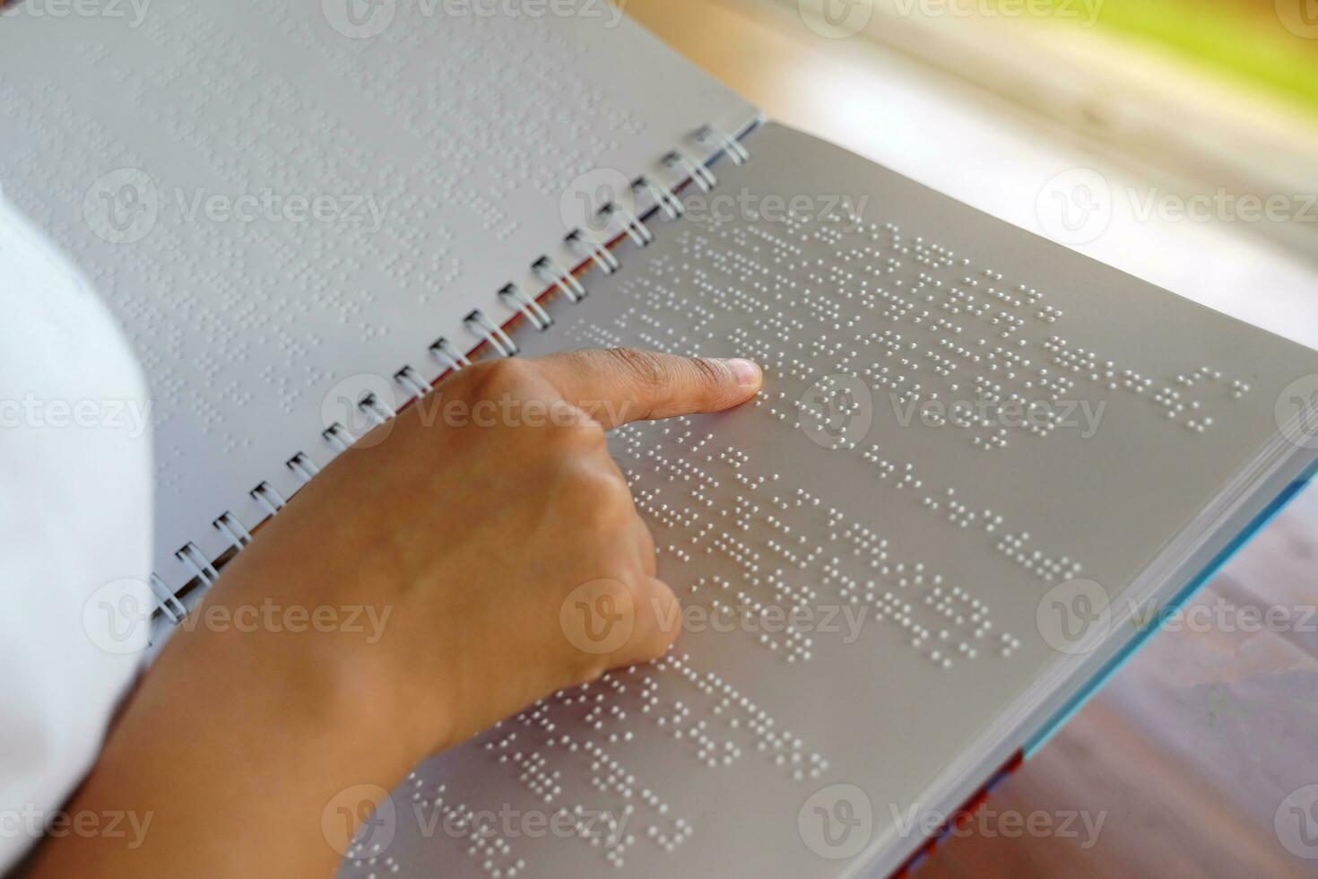 visuellement altéré la personne lit avec le sien les doigts une livre écrit dans braille il est écrit pour ceux qui sont visuellement altéré ou aveugle. il est une spécial code généré de 6 points dans le boîte. photo