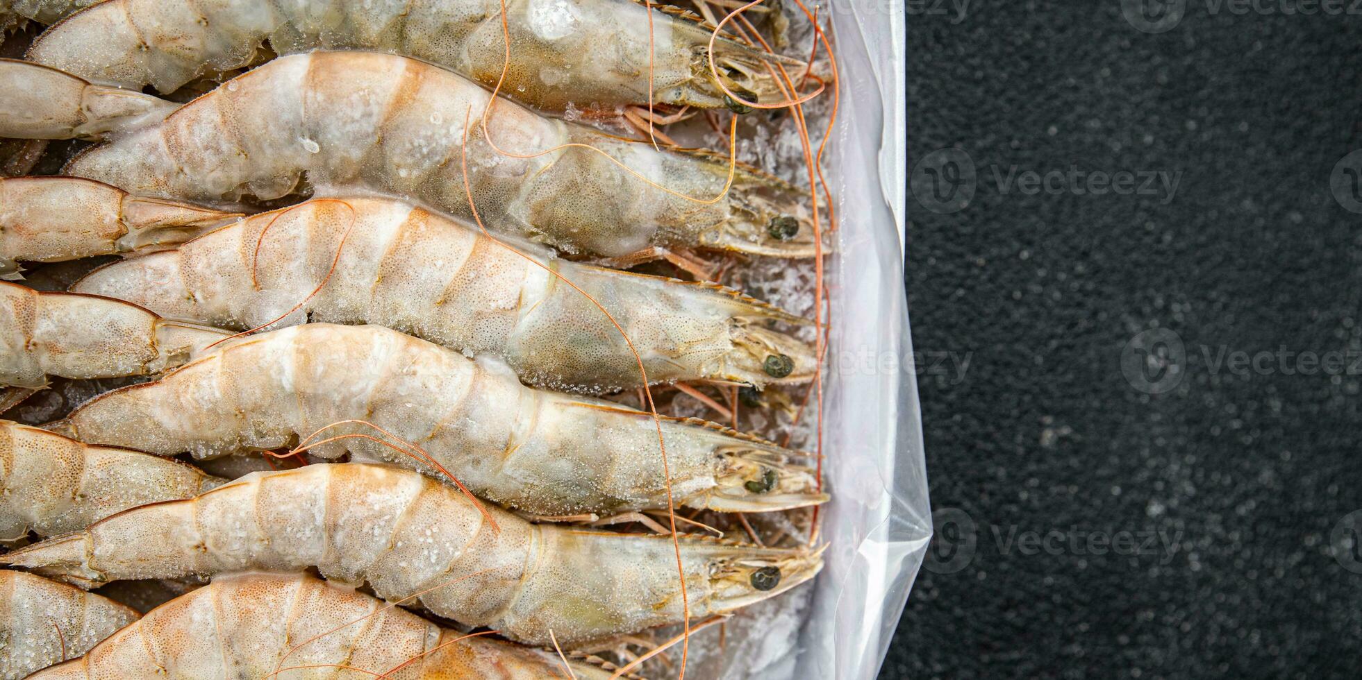 Gambas brut congelé dans la glace gros crevette Fruit de mer crevette repas nourriture casse-croûte pescatarian régime sur le table copie espace nourriture Contexte rustique Haut vue céto ou paléo photo