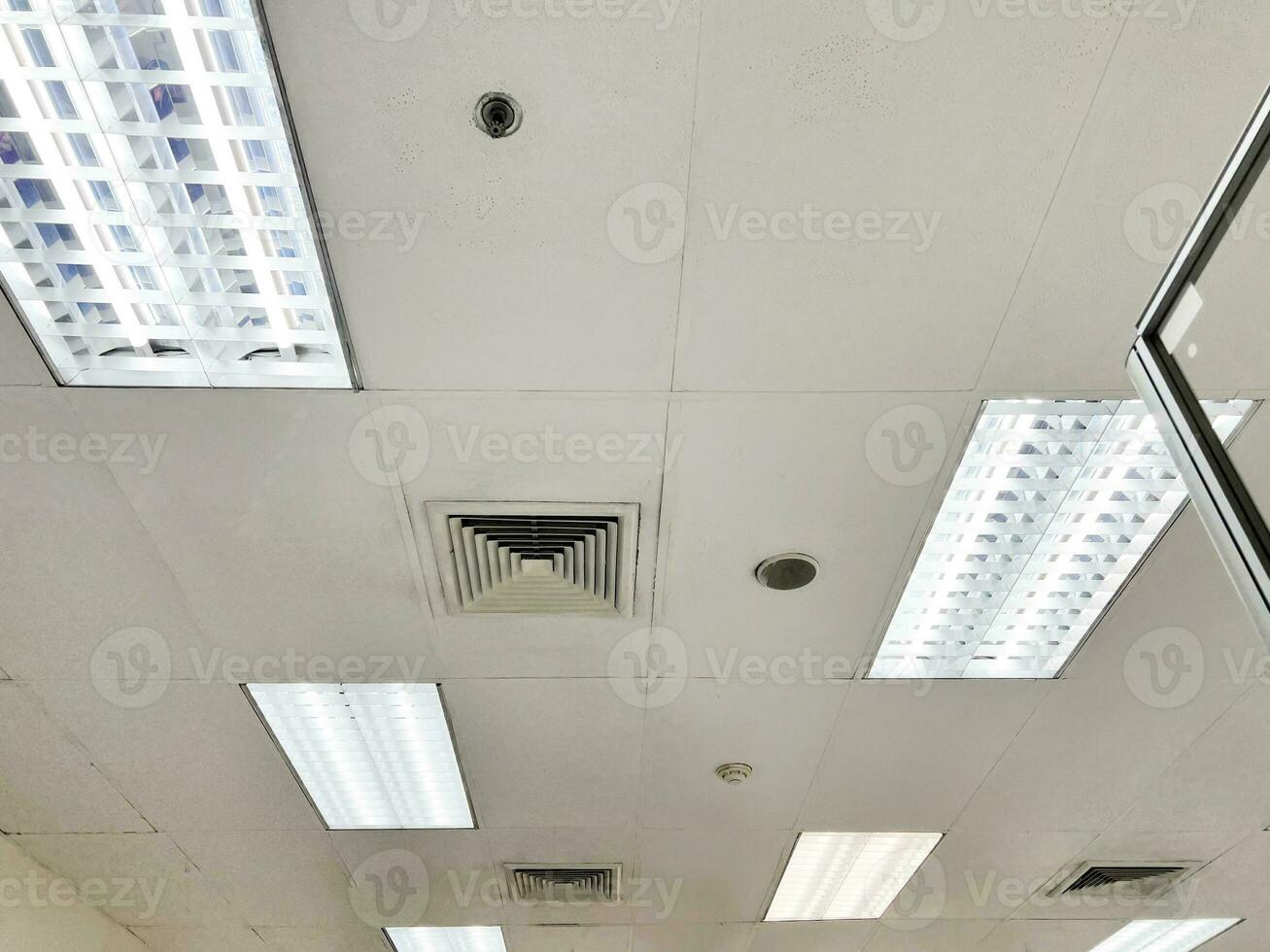 climatiseur de type cassette monté au plafond et lampe moderne au plafond blanc. climatiseur gainable pour la maison ou le bureau photo
