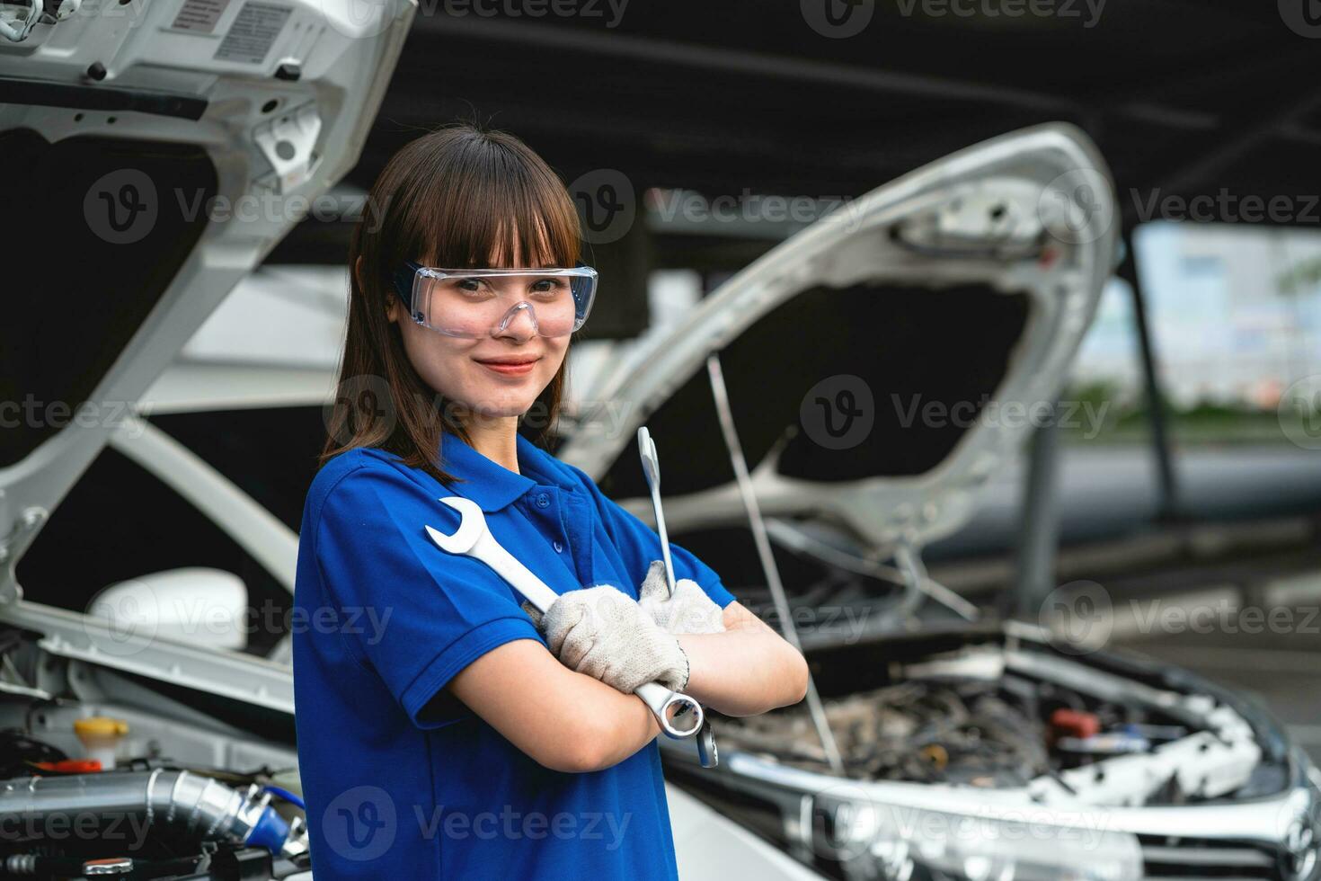 centre de service de réparation automobile, une mécanicienne heureuse debout près de la voiture. mécanicien automobile femme asiatique portant une chemise aquarelle dans le garage. femme heureuse mécanicienne dans un centre de service de réparation automobile. photo