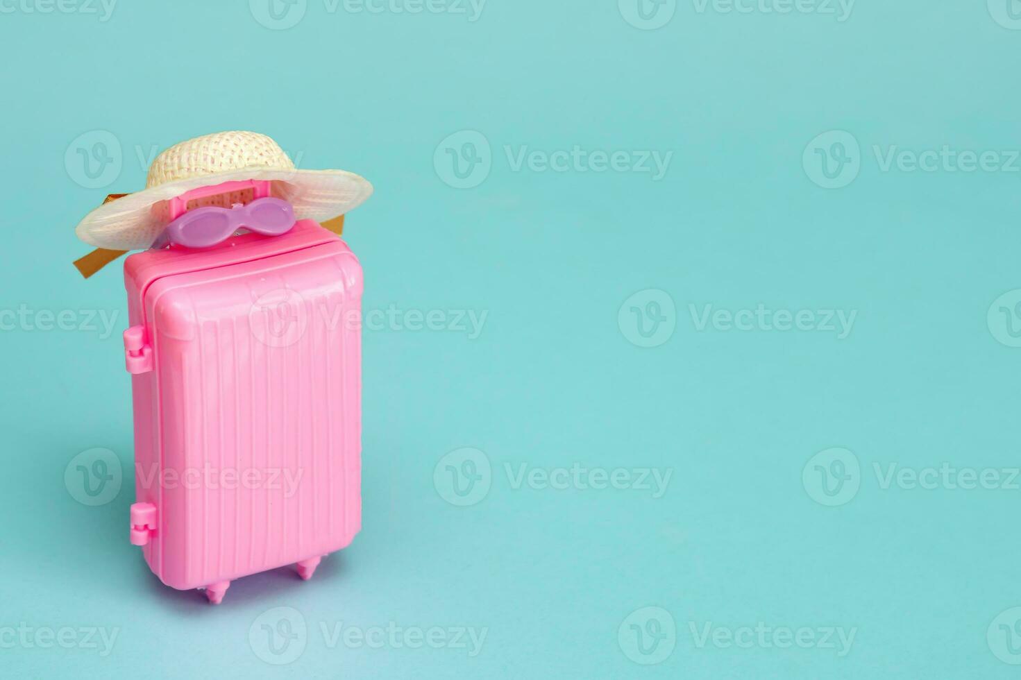 jouet valise avec des lunettes de soleil et une chapeau sur une lumière turquoise Contexte avec copie espace, Voyage contenu photo