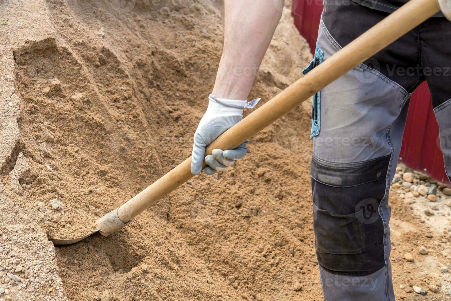 homme prend une pelle de le sable de un digue photo