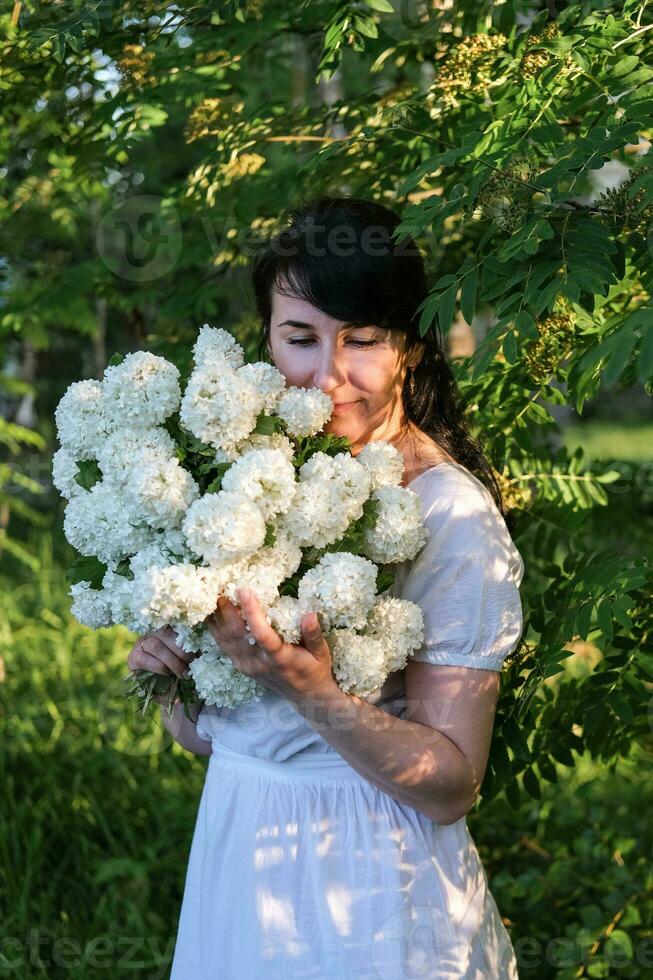 romantique portrait de une Jeune femme avec une bouquet de blanc fleurs dans une été jardin. été mode de vie photo