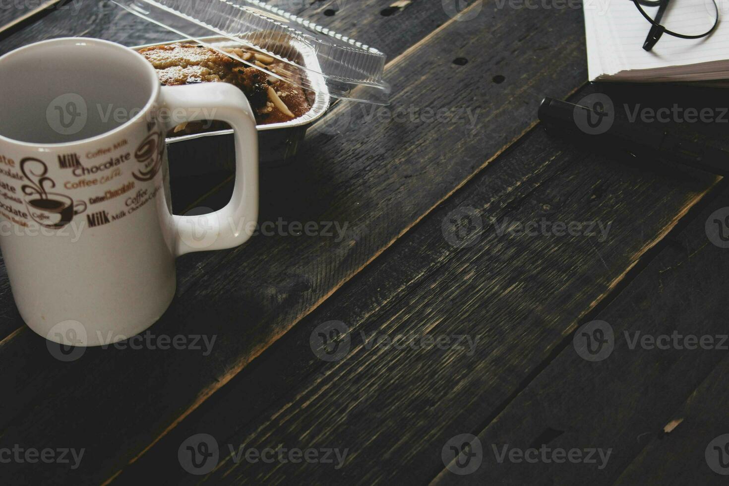 banane gâteau sur une noir en bois table avec Remarque livre, lunettes, et café tasses. photo