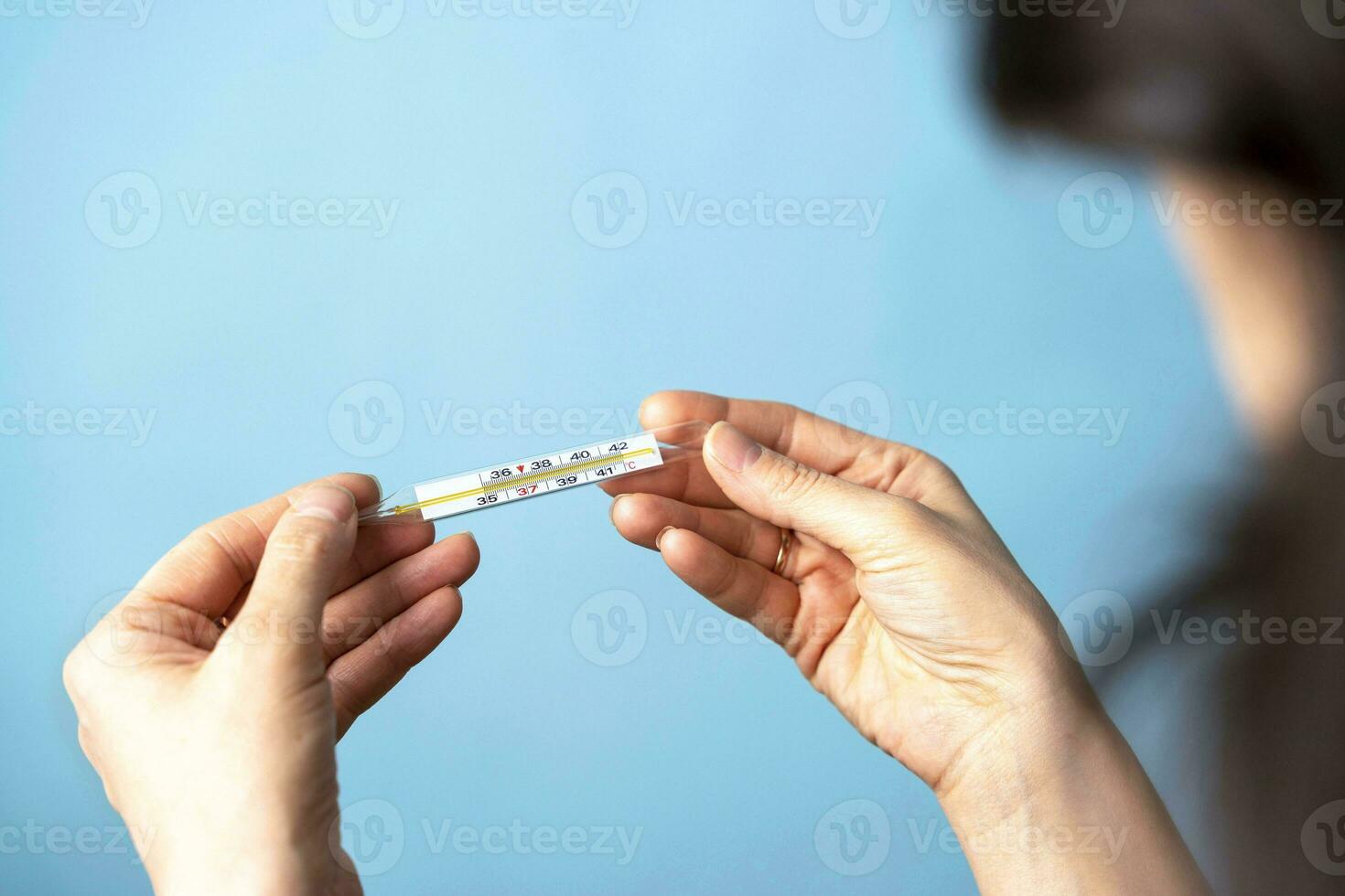 aux femmes mains tenir une médical thermomètre, bleu Contexte. soins de santé concept photo