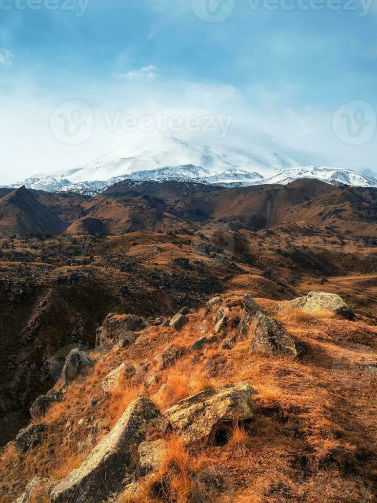 brillant blanc neigeux de pointe de monter elbrus au dessus le l'automne rocheux plateau. l'automne elbrouz. l'automne dans le Caucase montagnes. blanc neige gros montagnes. neige pics. verticale voir. photo