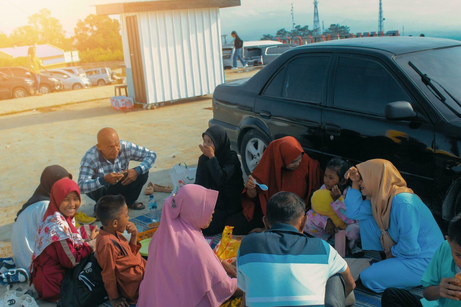 Karo, Indonésie, avril 2023 - famille profiter été pique-nique le déjeuner dans retour de auto. adultes servir nourriture à leur les enfants. photo