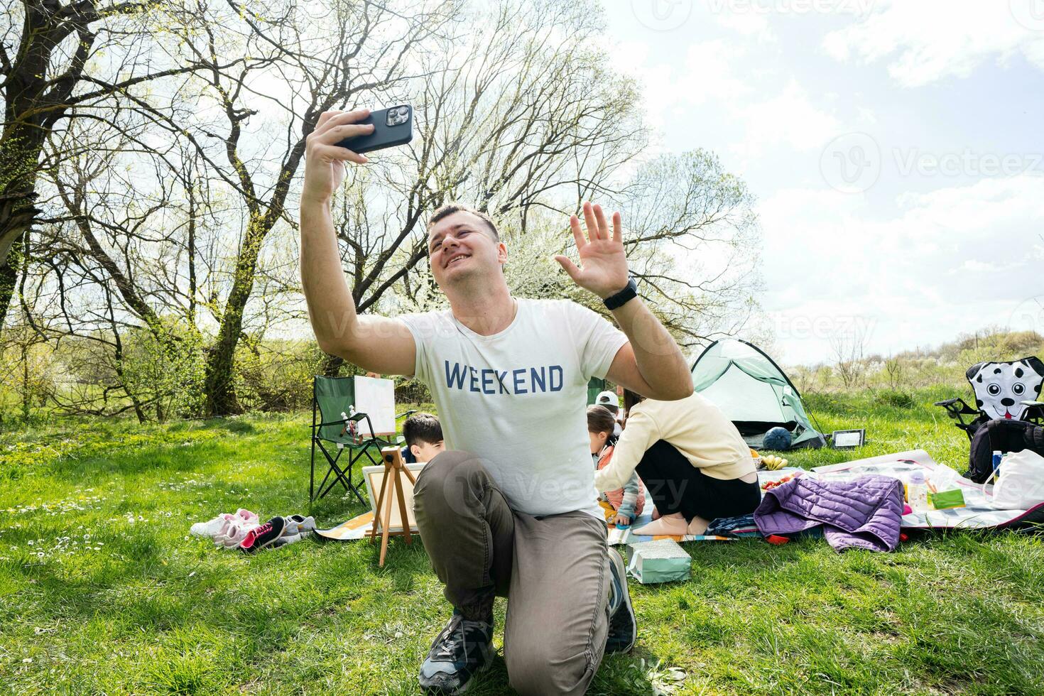 papa court une vlog. content Jeune famille ayant amusement et profiter Extérieur sur pique-nique couverture à jardin printemps parc, relaxation. photo