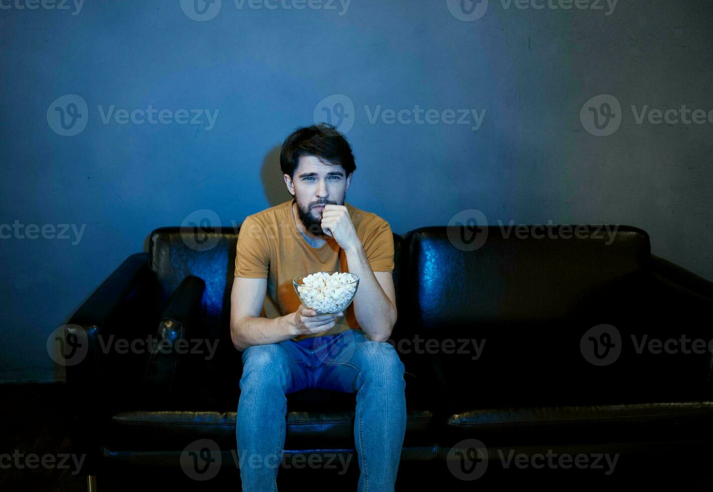 solitaire homme séance sur canapé avec pop corn assiettes gris mur photo