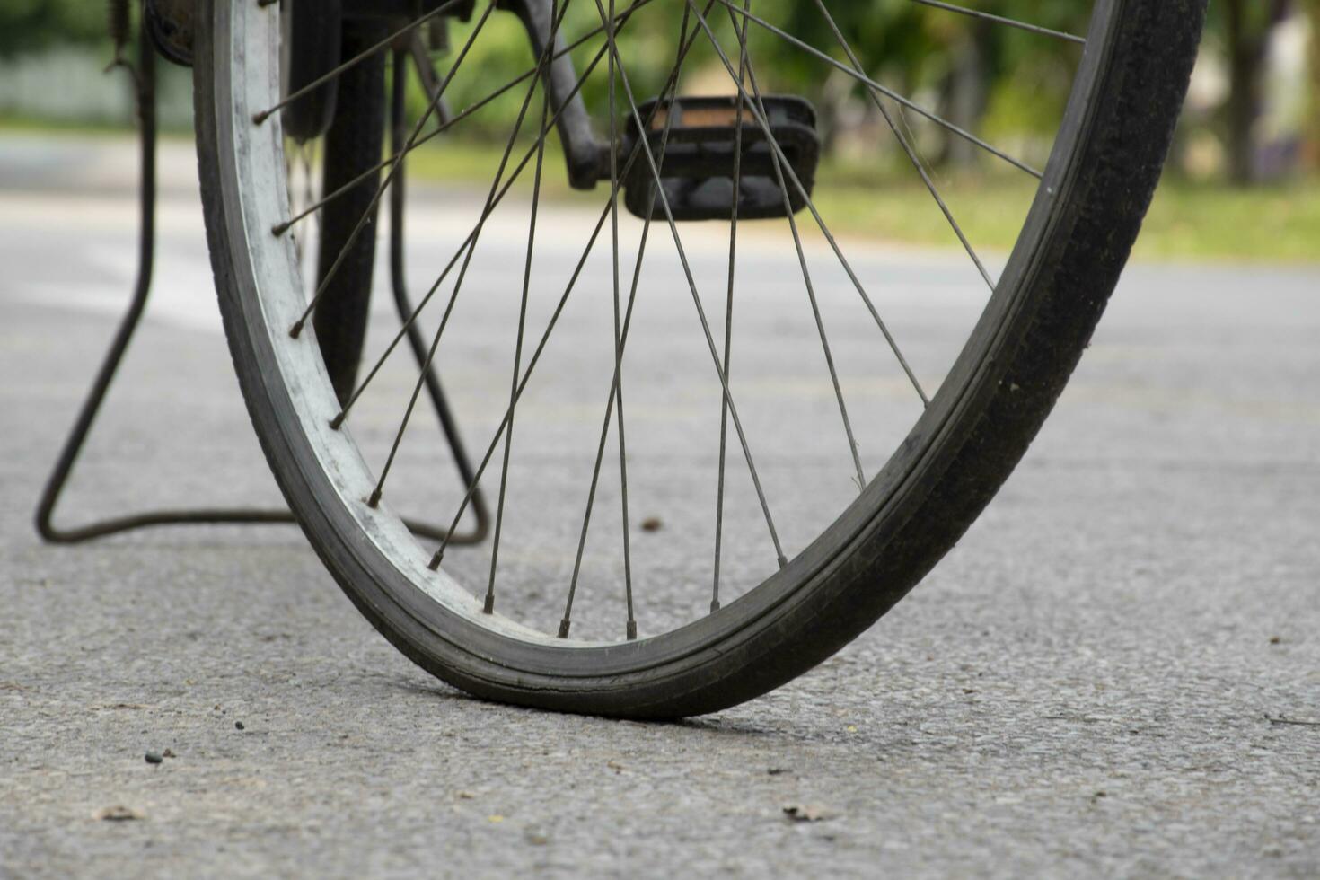 fermer vue de ancien bicyclette lequel a plat roues et garé sur ciment sol de rue près le bâtiment, doux se concentrer. photo