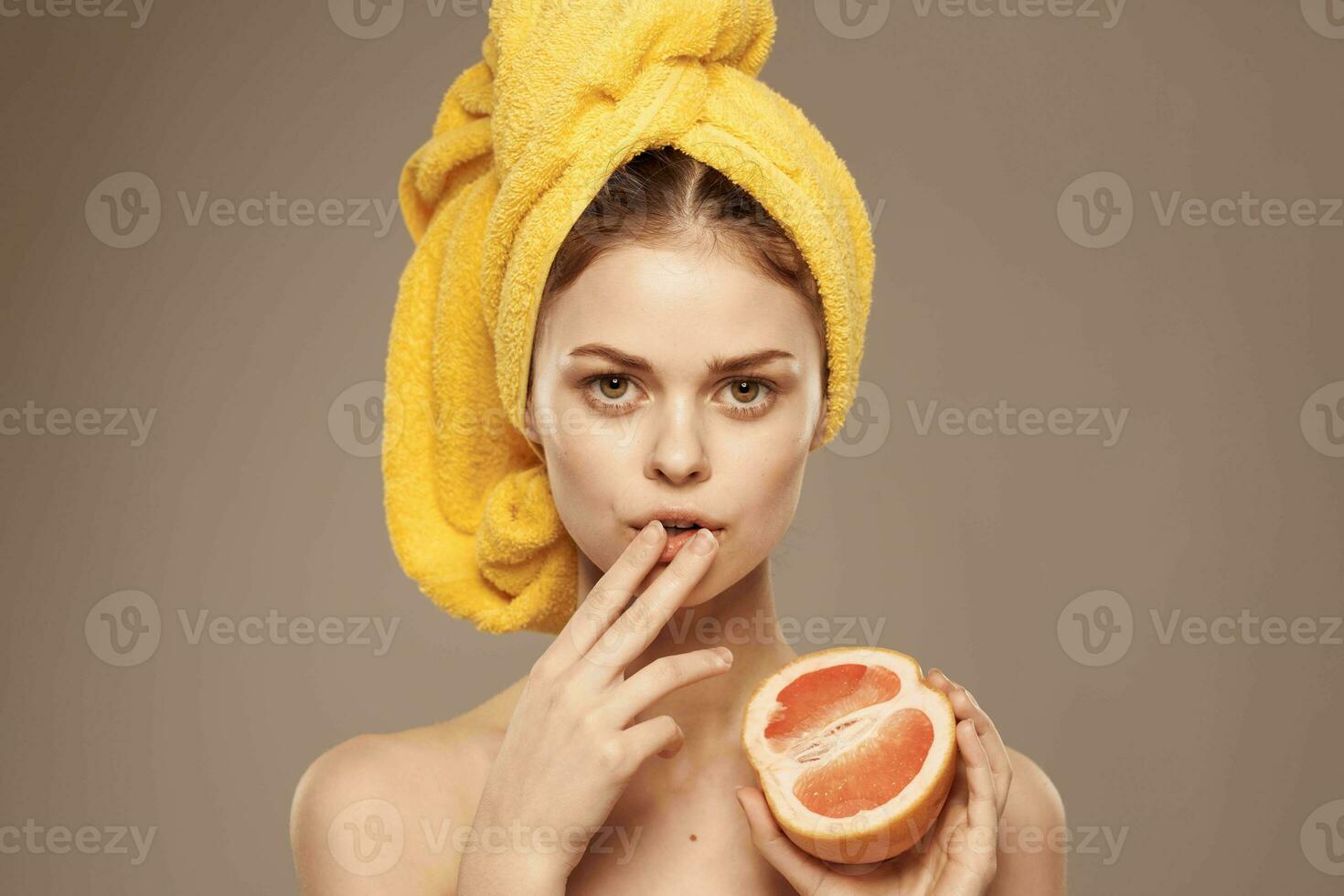 de bonne humeur femme avec une Jaune serviette sur sa tête nu épaules pamplemousse dans main Naturel produits de beauté photo