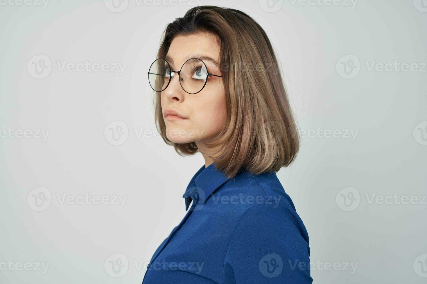 élégant femme avec des lunettes dans bleu chemise mode lumière Contexte photo