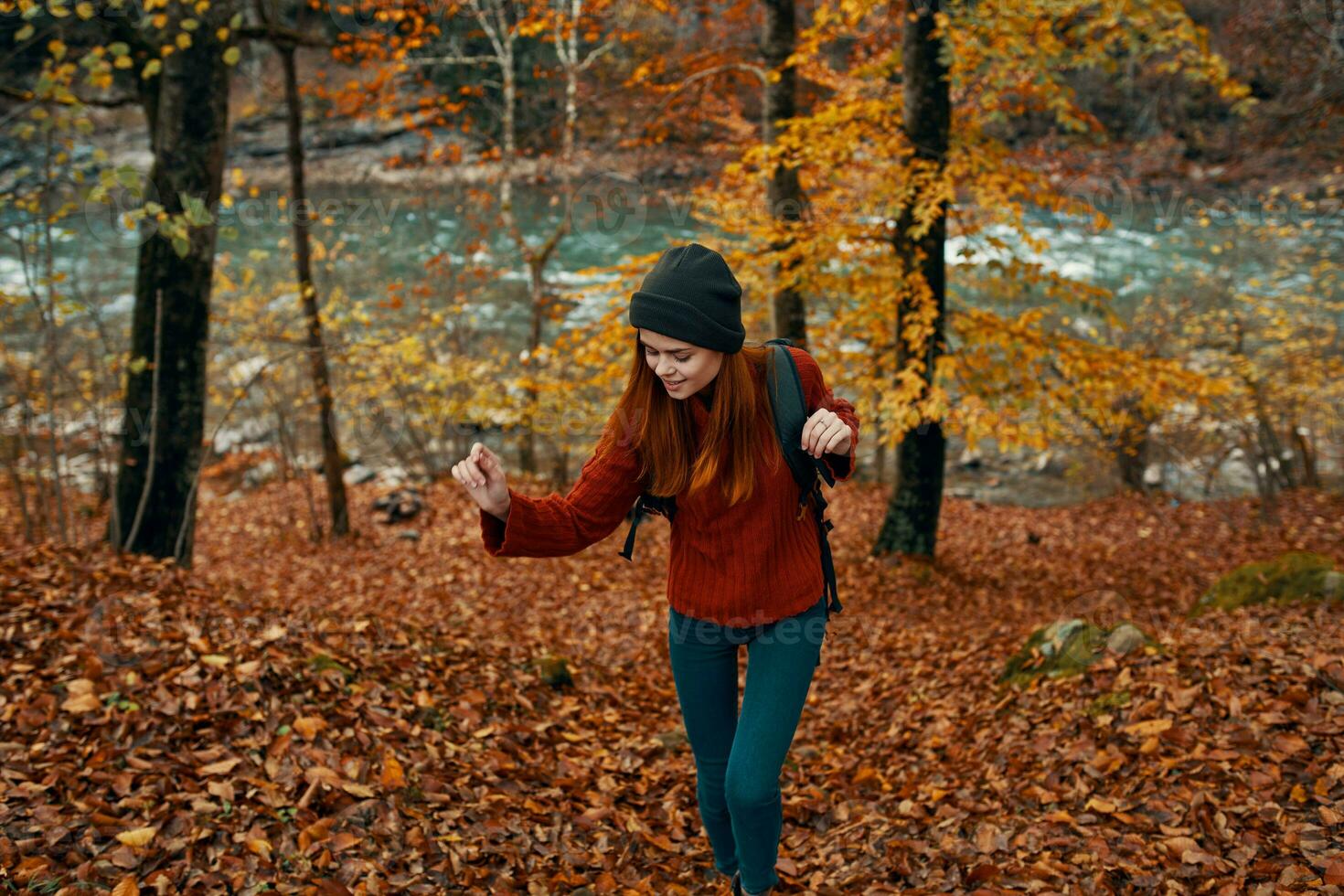 femme dans une chandail avec une sac à dos repos dans une parc près le rivière dans la nature dans l'automne photo