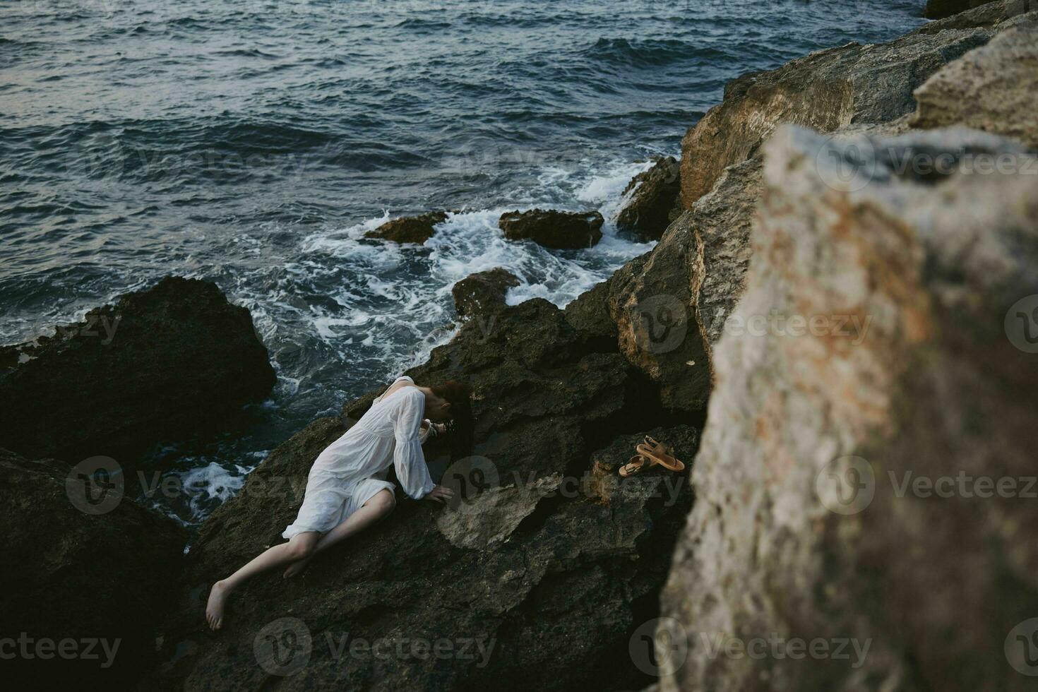 pieds nus femme mensonge sur sa retour sur une rocheux rivage inchangé photo