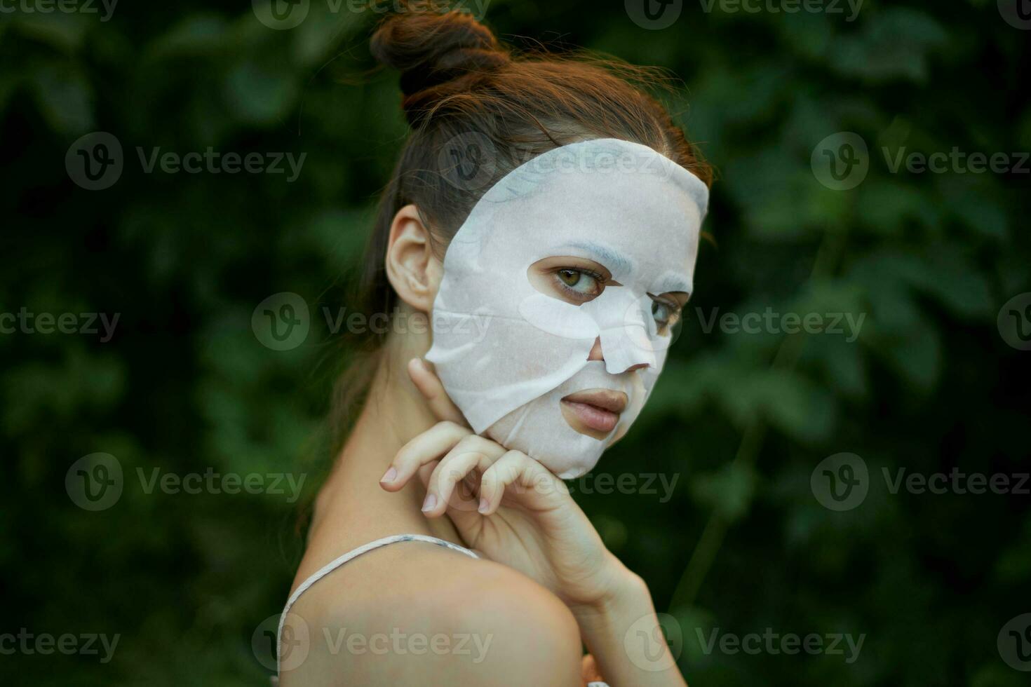 portrait de une femme touche le sien épaule avec le sien main blanc masque peau se soucier des buissons dans le Contexte photo