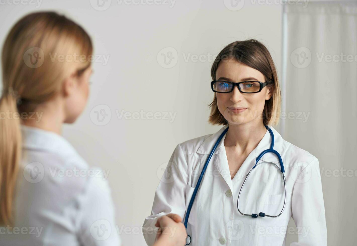 médecin et patient tremblement mains sur une lumière Contexte stéthoscope autour le cou photo