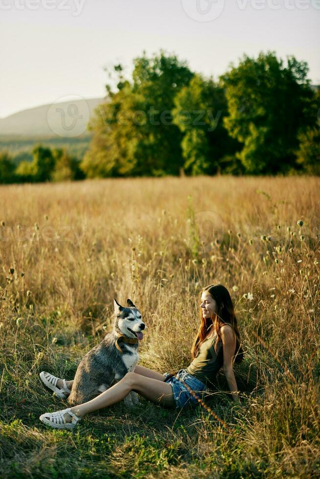 femme séance dans une champ avec une teckel chien souriant tandis que dépenses temps dans la nature avec une ami chien dans l'automne à le coucher du soleil photo