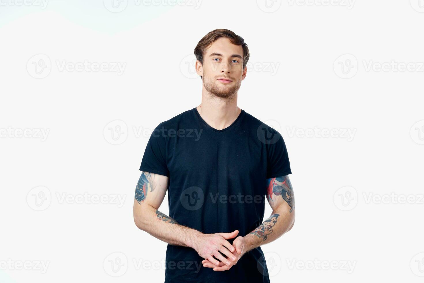 musclé homme dans une bleu T-shirt avec tatouages sur le sien bras sur une lumière Contexte tondu vue photo