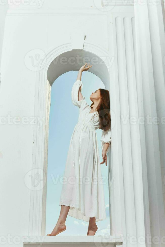 une femme dans une blanc robe des stands dans une fenêtre ouverture posant photo