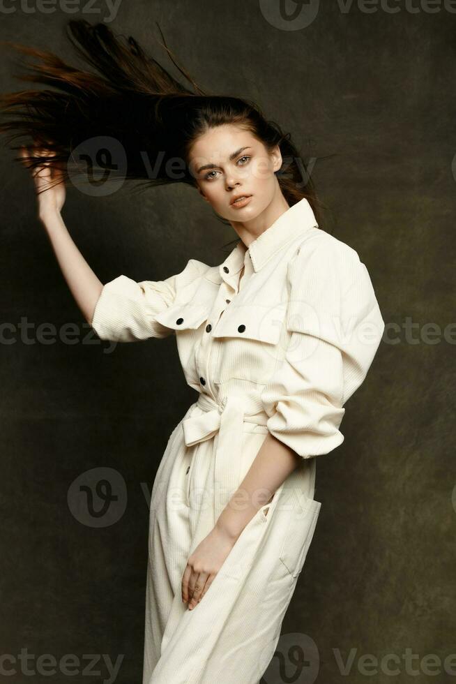 portrait de une femme dans une blanc combinaison sur une foncé Contexte costume posant modèle photo