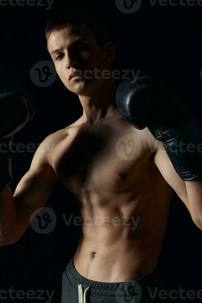 boxeur dans noir gants sur une foncé Contexte gonflé torse bodybuilder photo