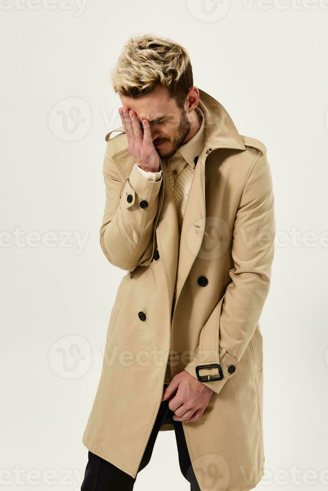 homme dans beige manteau détient main près visage émotions studio photo