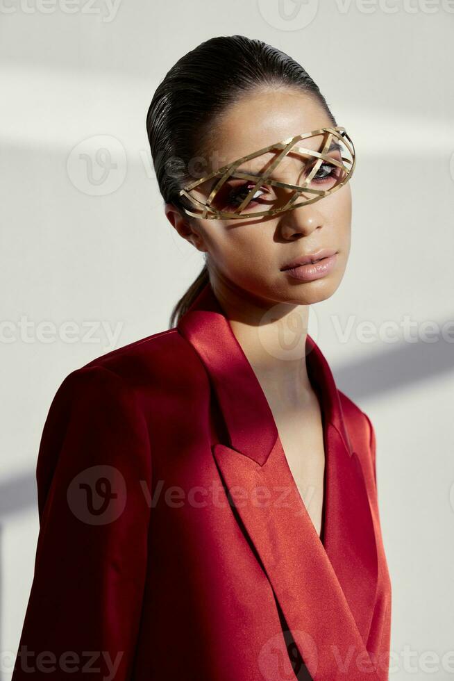 portrait de une élégant femme dans une rouge veste et bijoux sur sa visage le fer des lunettes Nouveau La technologie photo