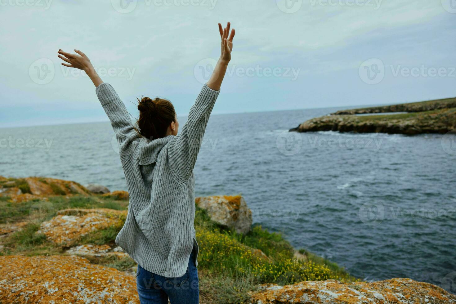 jolie femme dans une gris chandail des stands sur une rocheux rive la nature relaxation concept photo