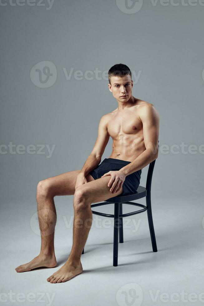 sportif homme dans noir short séance sur une chaise gymnastique salle du repos photo