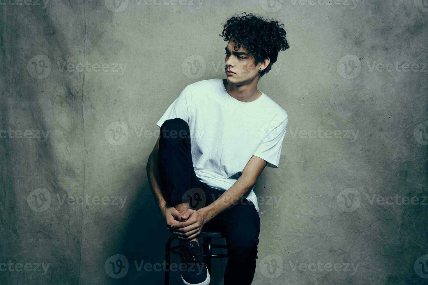 homme avec frisé cheveux séance sur une chaise mode studio photo