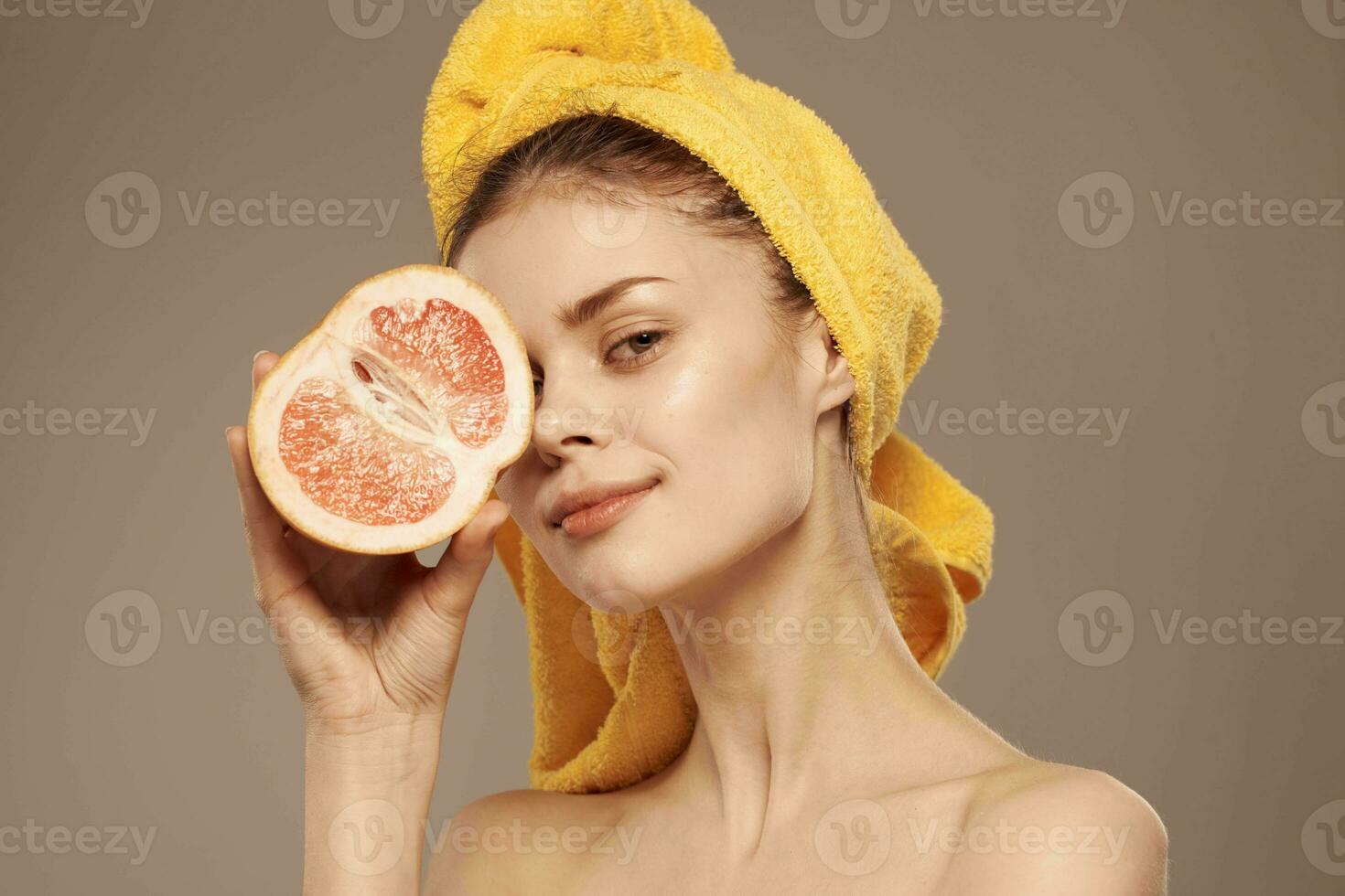 jolie femme avec serviette sur sa tête nettoyer peau à nu épaules agrumes fruit dans mains photo