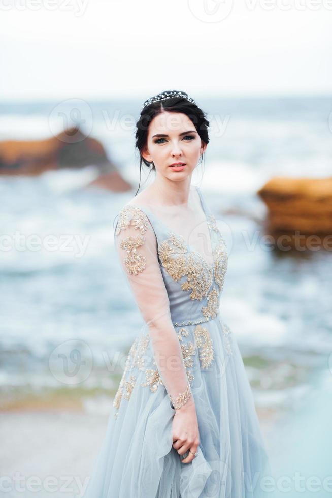 mariée dans une robe de lumière bleue marchant le long de l'océan photo