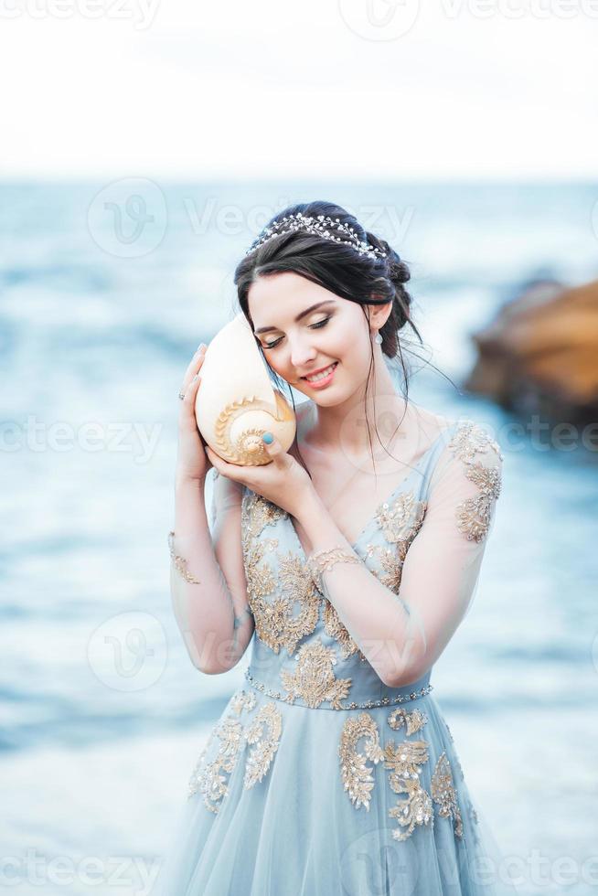 mariée avec une grosse coquille sur la plage photo