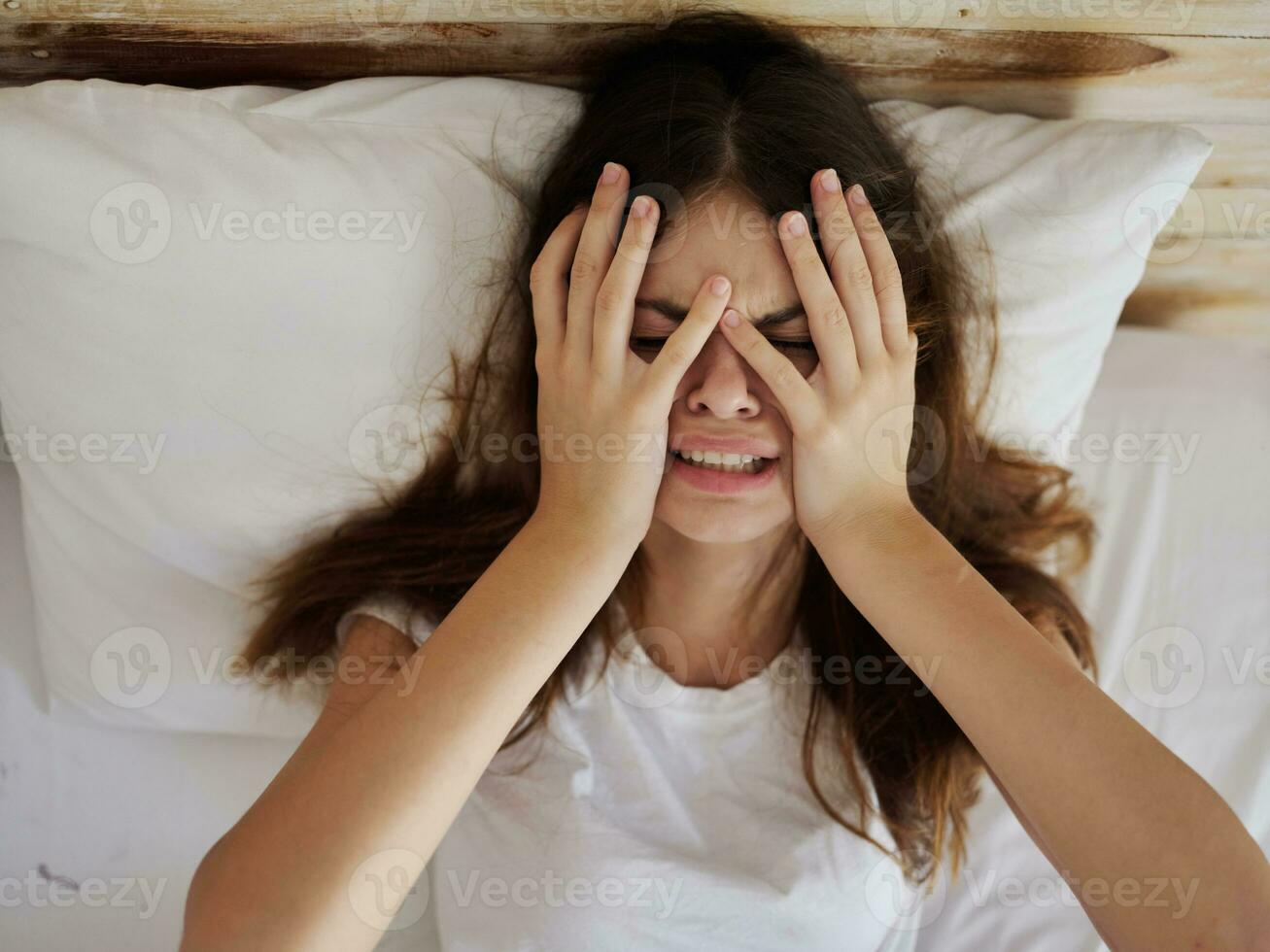 femme en portant mains sur visage dérangé pleurs mensonge dans lit photo