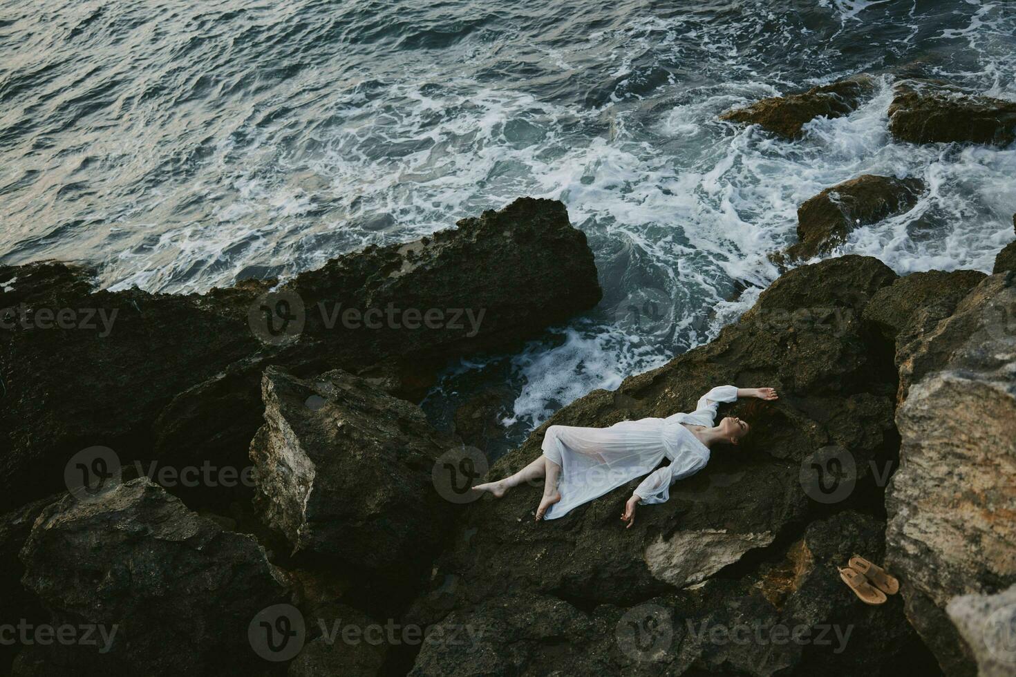 femme dans une blanc robe mensonge sur une pierre dans une blanc robe paysage photo