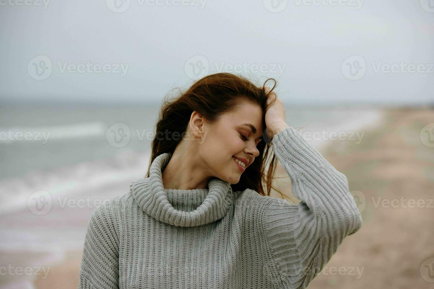 magnifique femme dans une chandail en volant cheveux par le océan tourisme mode de vie photo